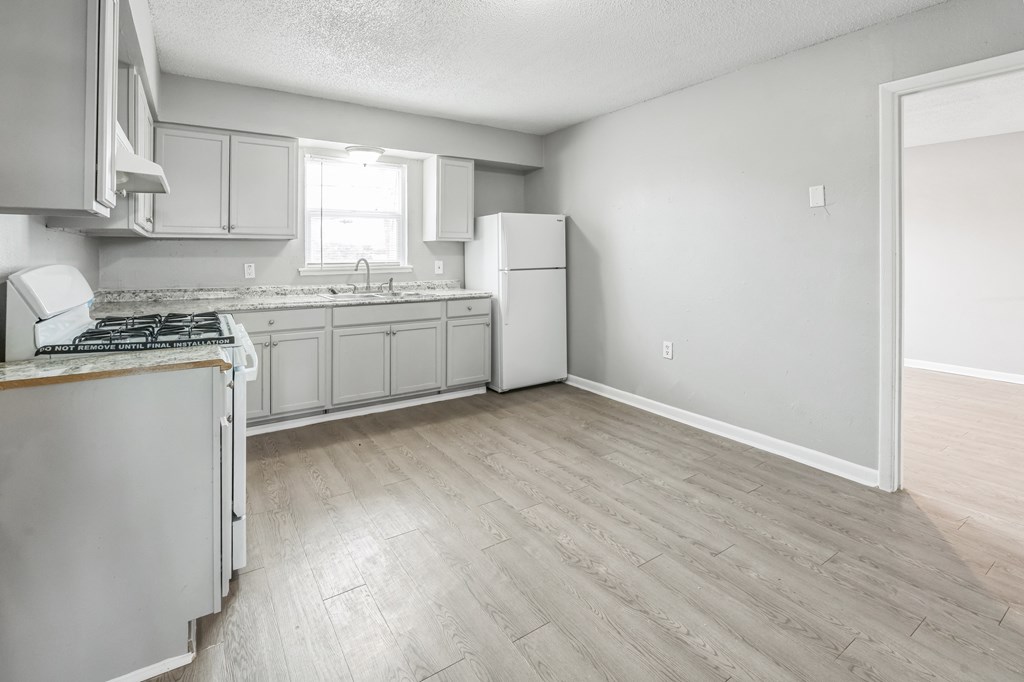 A kitchen with a stove, sink, and refrigerator.