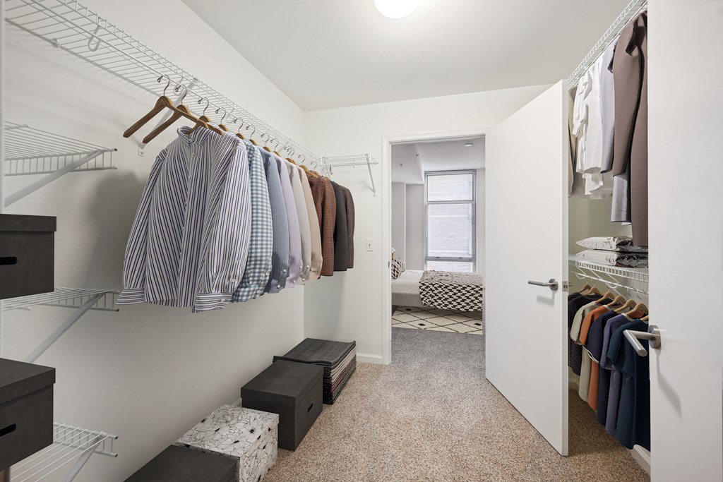 a walk in closet with clothes hanging on a rack and a door to a bedroom
