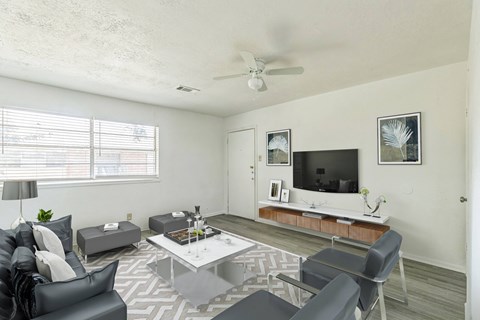 A living room with a black couch, a white coffee table, and a television on a wooden stand.