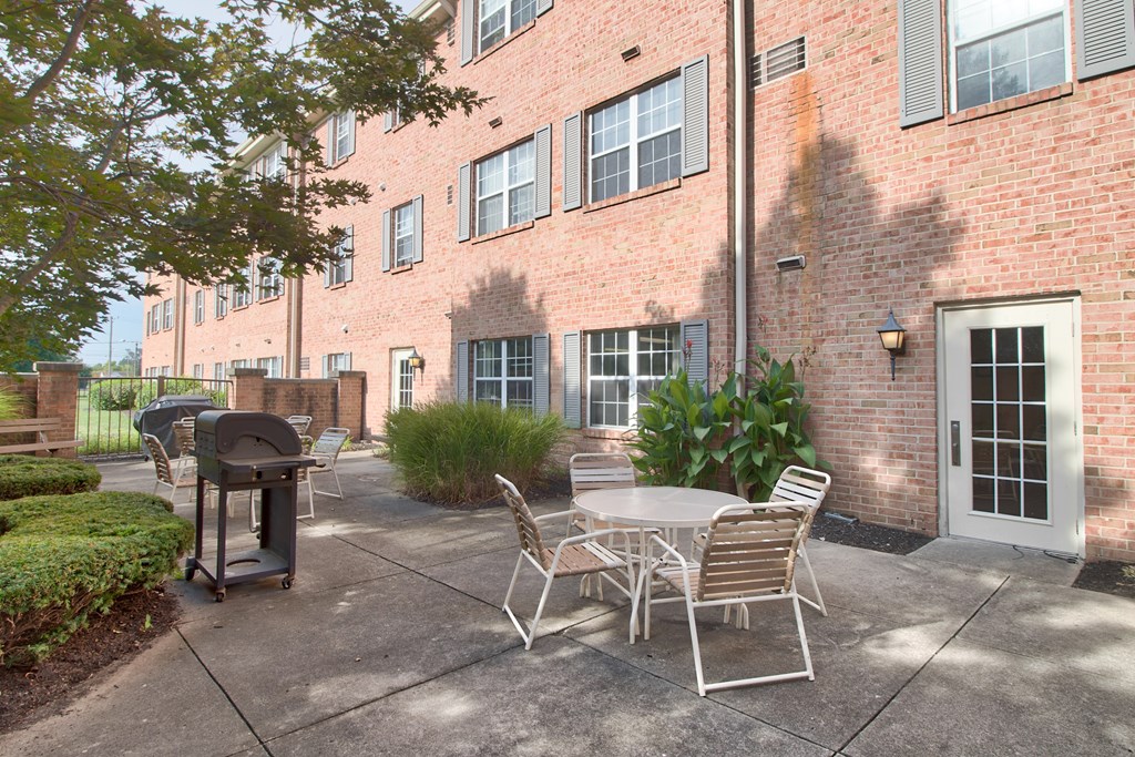 A patio with a table and chairs is in front of a brick building.