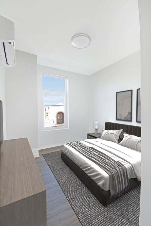 A bedroom with a large bed and a window overlooking a cityscape.
