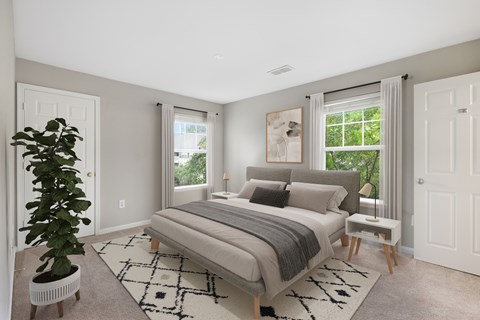 A bedroom with a large bed and a plant in a white pot.