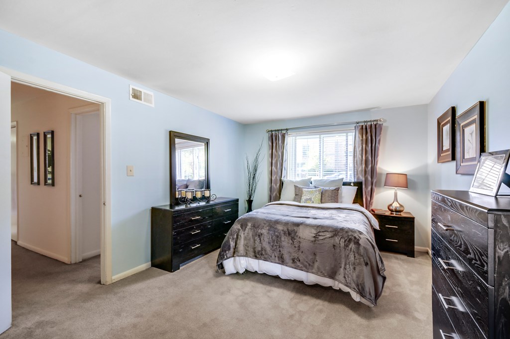 A bedroom with a bed, dresser, and mirror.