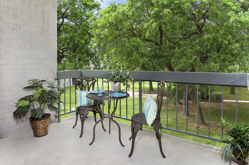 A patio with a table and chairs overlooking a green area.
