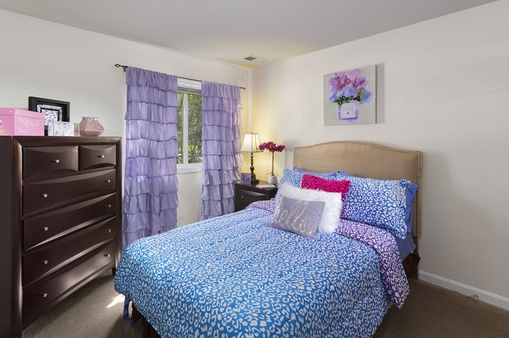 A bedroom with a blue patterned bedspread and matching curtains.