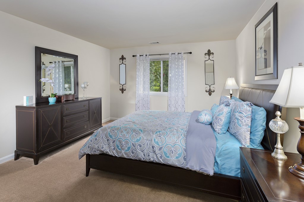 A bedroom with a bed, nightstand, and a dresser.