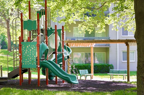A playground with a green slide and a red structure.