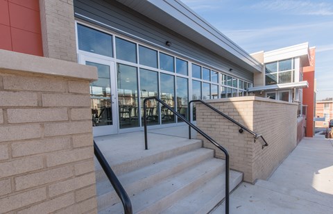 A building with a staircase leading to a glass door entrance.