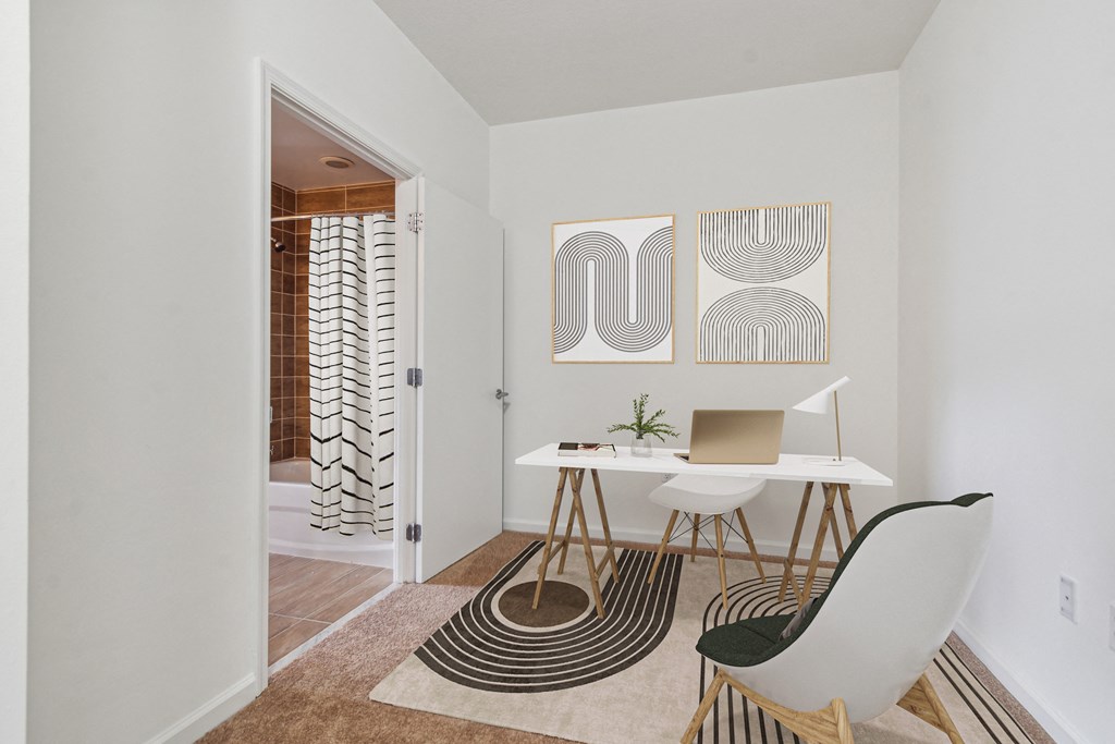 a home office with a desk and chair and a door to a bathroom