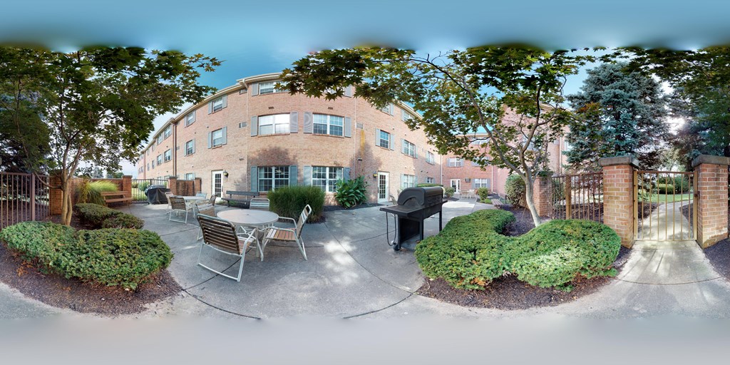 A courtyard with a table and chairs surrounded by a brick building.