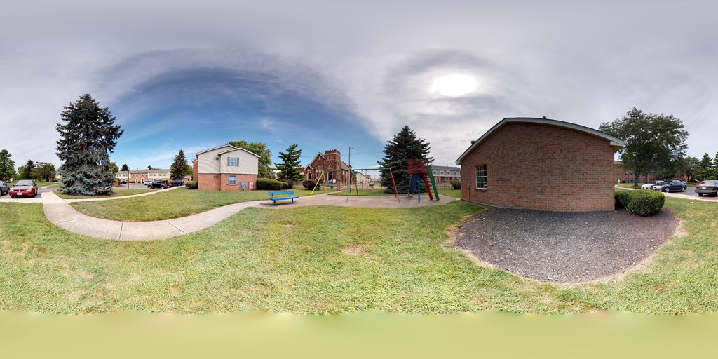 A playground with a slide and a small building is surrounded by a grassy area.