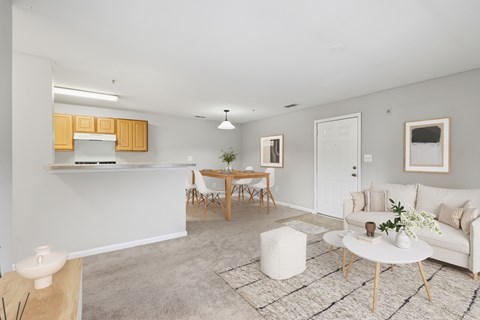 A living room with a white couch, a wooden table, and a rug.