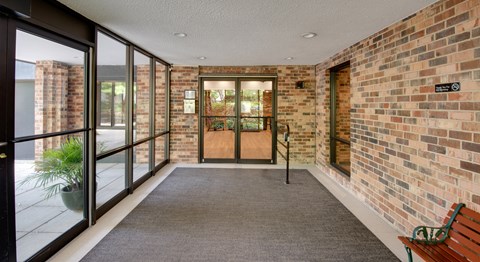 A hallway with a brick wall and a bench.