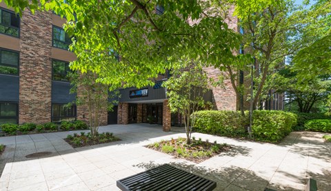 A courtyard with a brick building and a black bench.