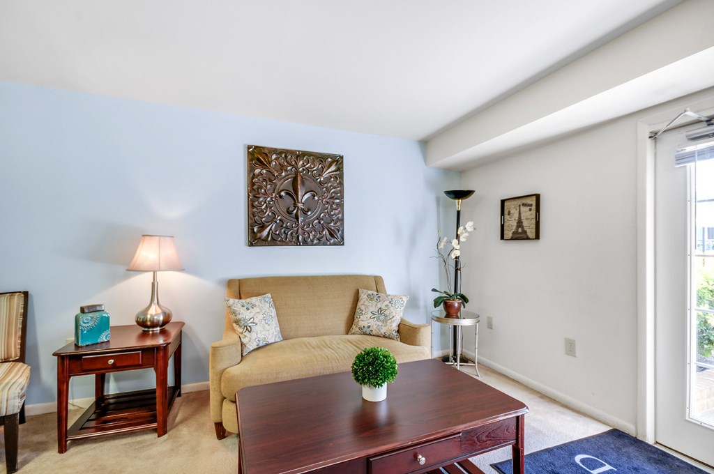 A living room with a brown couch, a wooden table, and a lamp.