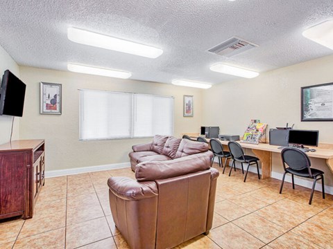 A living room with a brown couch, a wooden cabinet, and a desk with a computer.