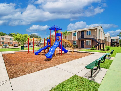 A playground with a blue slide and a green bench.