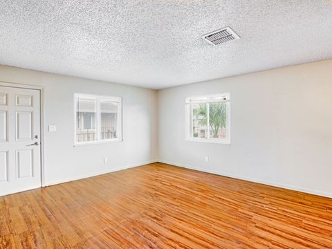 A room with wooden floors and two windows.