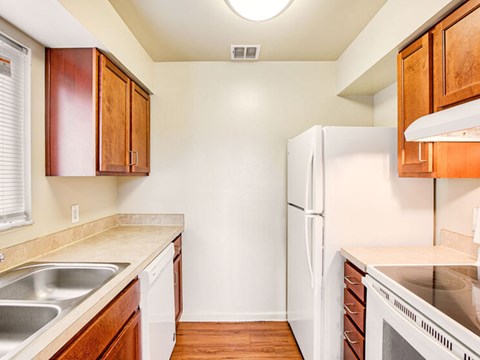 A kitchen with a white refrigerator, wooden cabinets, and a white oven.