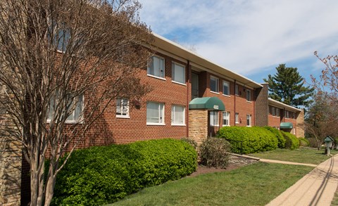 A brick building with a green awning sits on a street.