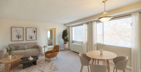 A living room with a grey couch, a wooden coffee table, a round table, and a chair.