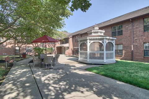 A patio with a table and chairs and a gazebo.