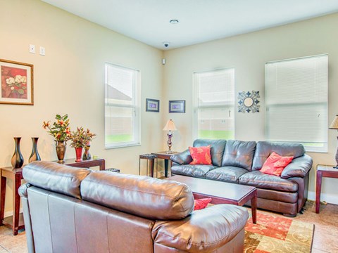 A living room with a brown leather couch and a grey one.