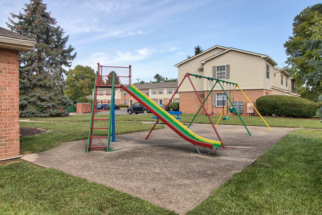 A playground with a green, yellow and red slide.