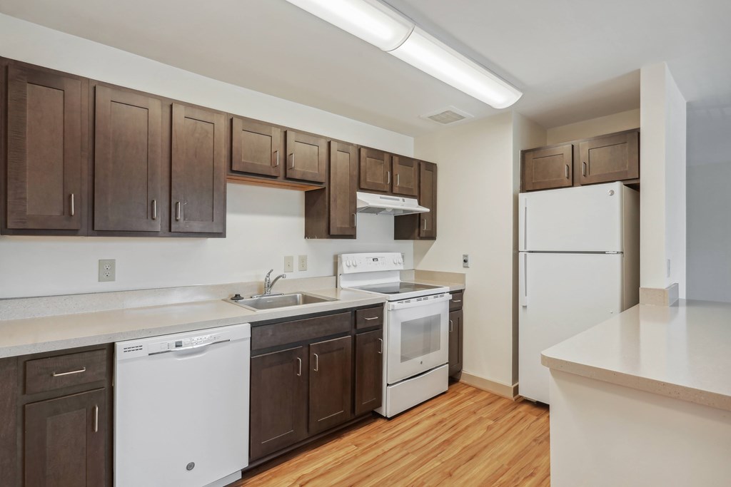 A kitchen with white appliances and brown cabinets.