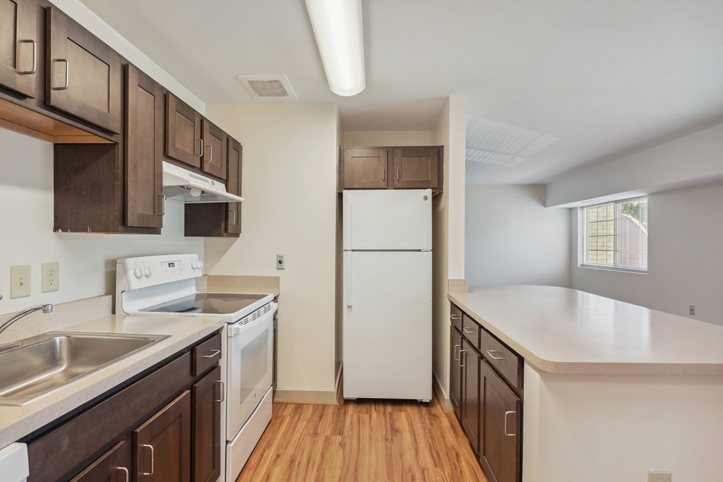 A kitchen with white appliances and wooden cabinets.