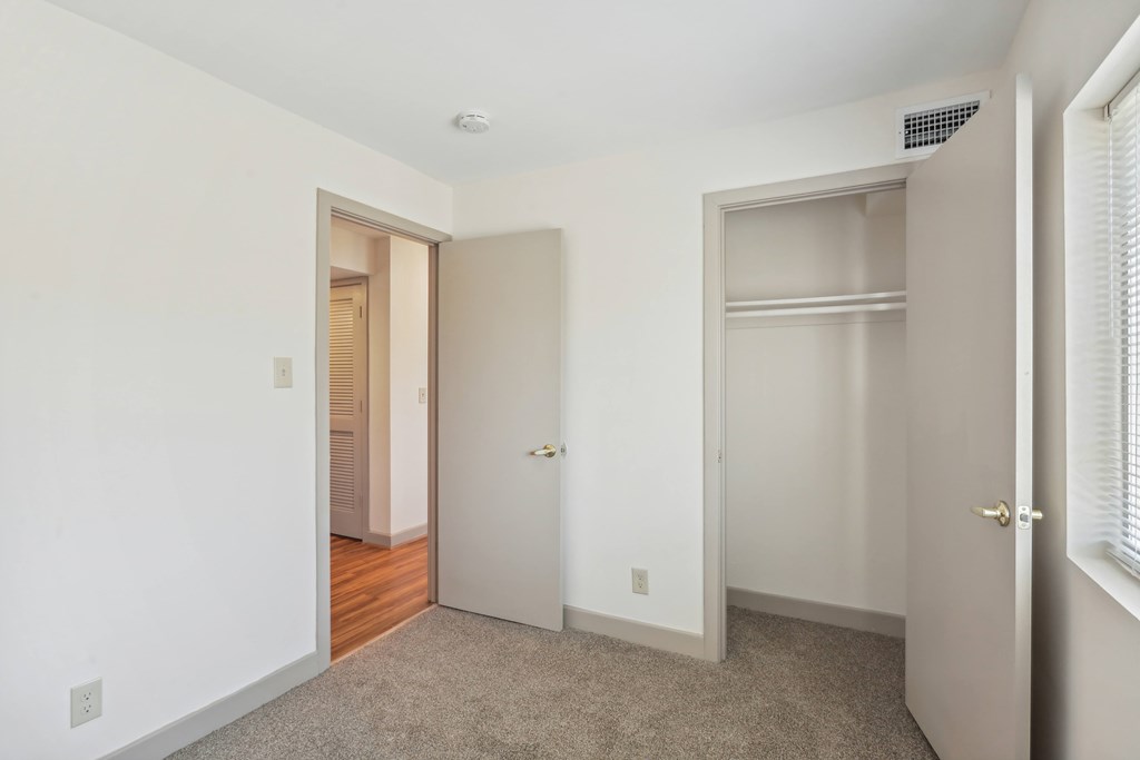 A white room with a carpeted floor and two doors.