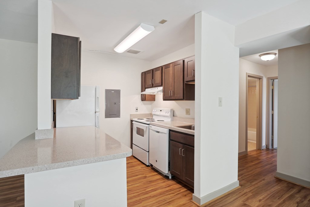 A kitchen with white countertops and wooden floors.