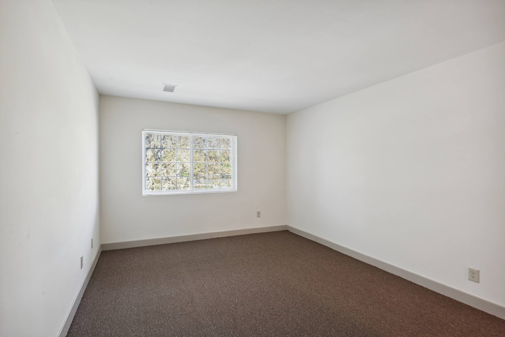 A room with a window and carpeted floor.