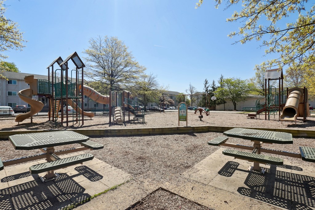 A playground with a slide, swings, and picnic tables.