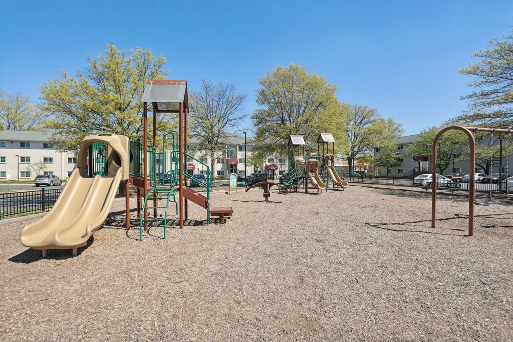 A playground with a slide, swings, and a seesaw.