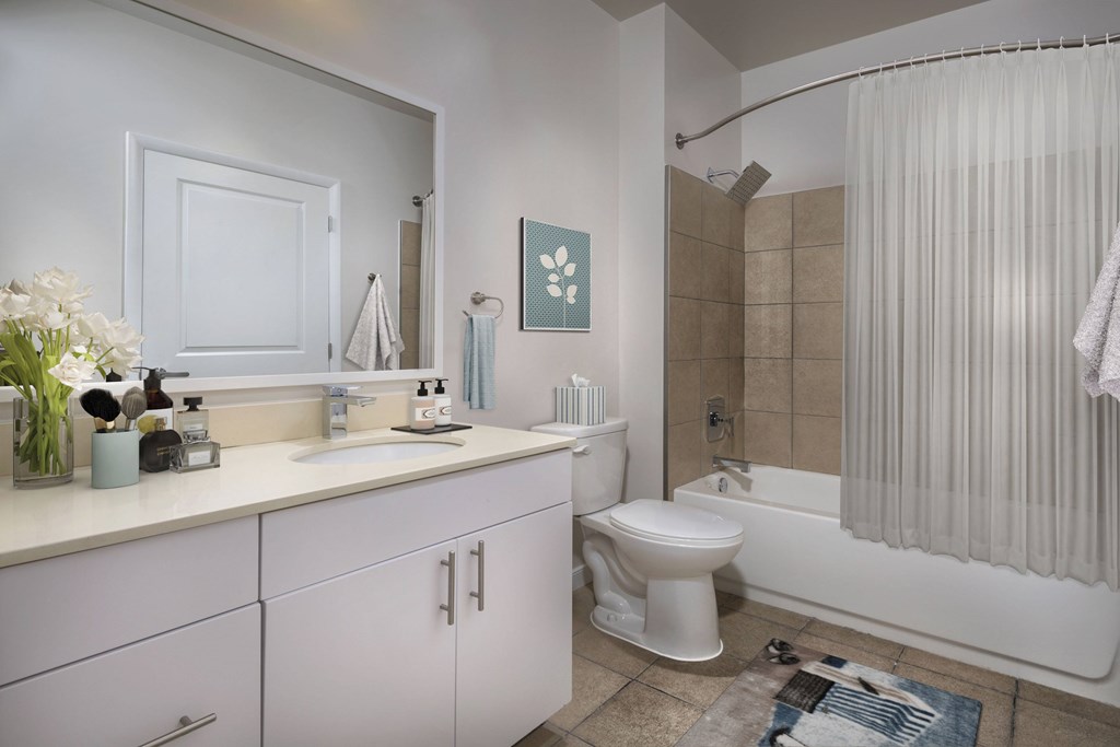 A white toilet is in a bathroom with a white tub and a white sink.