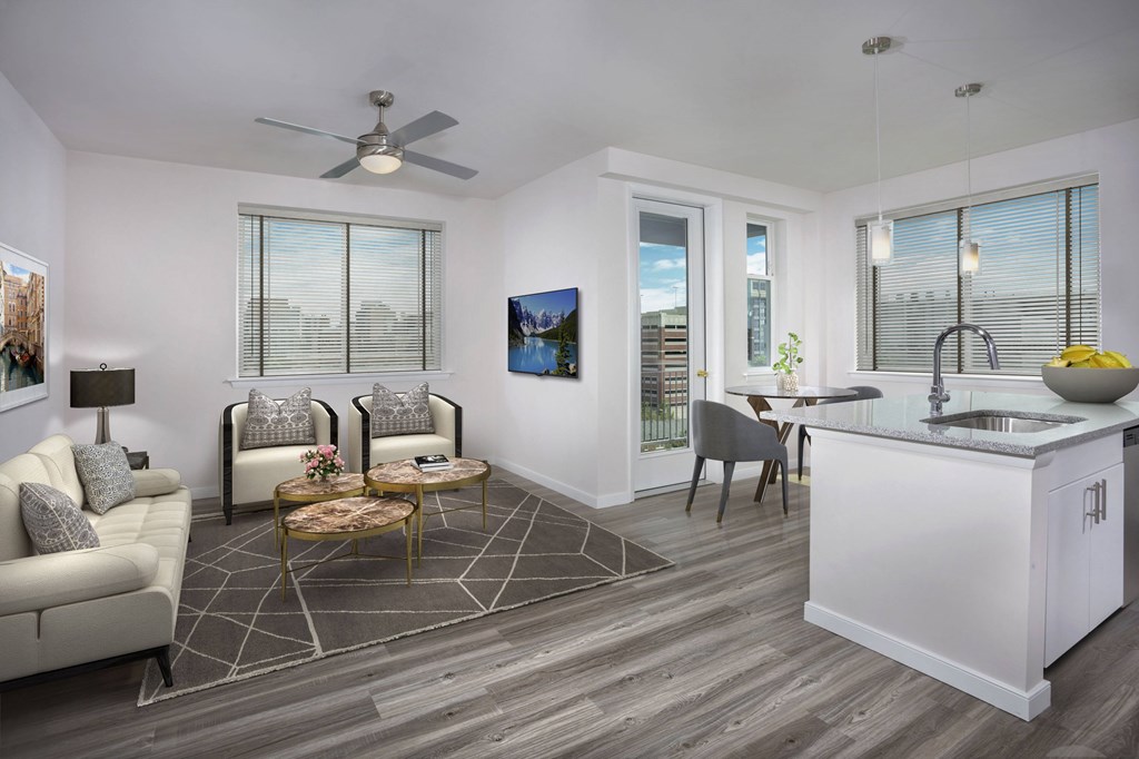 A modern living room with a white couch, a coffee table, and a kitchen area with a sink and a counter.