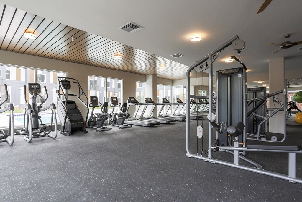 A gym with a variety of exercise equipment including treadmills, elliptical machines, and weight machines.