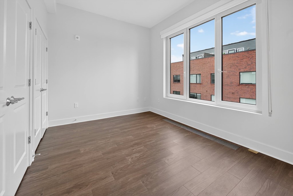 Empty room with a window overlooking a brick building.