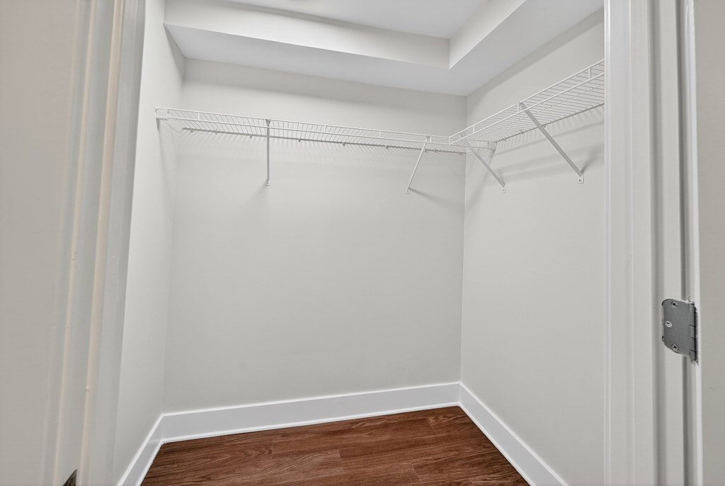 A white closet with a wooden floor and a white door.