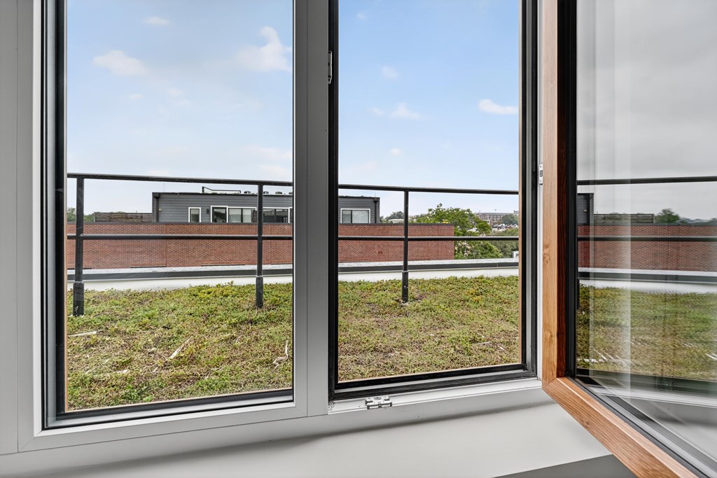 A view from a window looking out at a building and a grassy area.