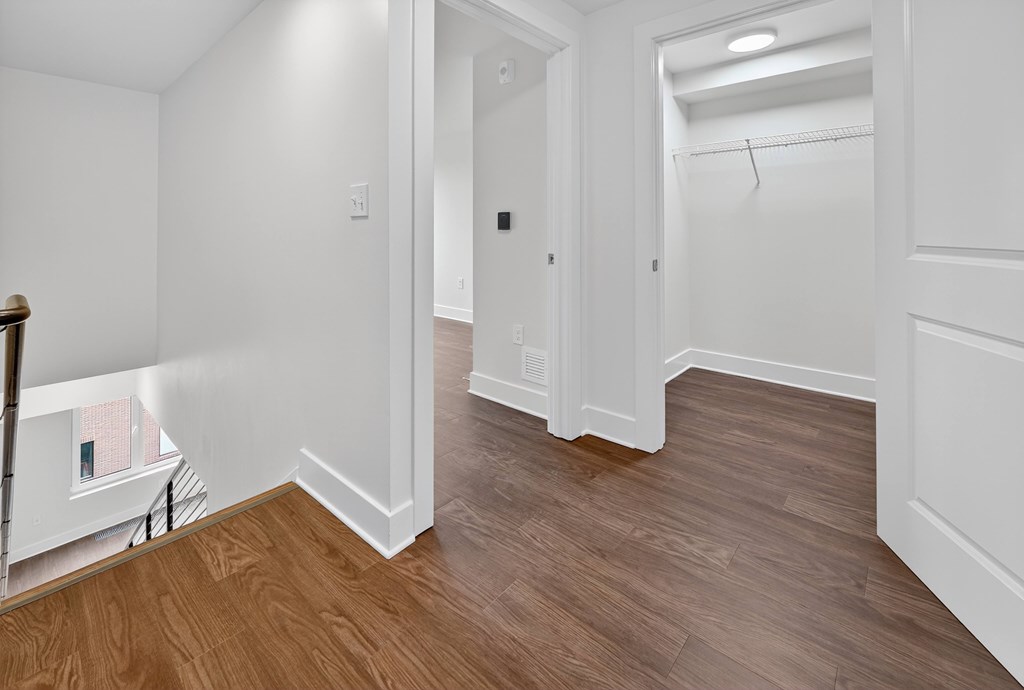 A hallway with wood floors and white walls.