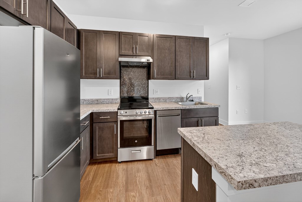 A kitchen with a refrigerator, oven, and sink.