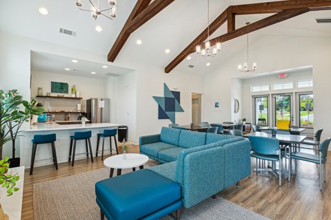 A modern living room with a blue sofa and a kitchen area in the background.