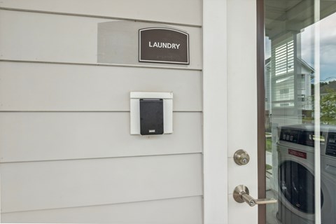 A washing machine is in the background of a door with a sign that says laundry.