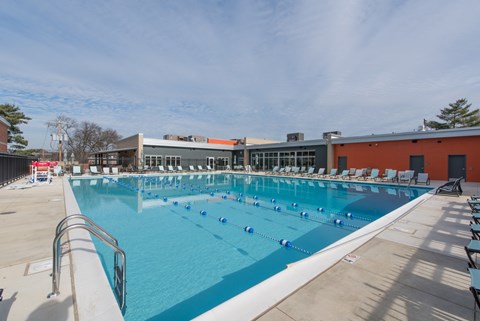 A large outdoor swimming pool with sun loungers and a building in the background.