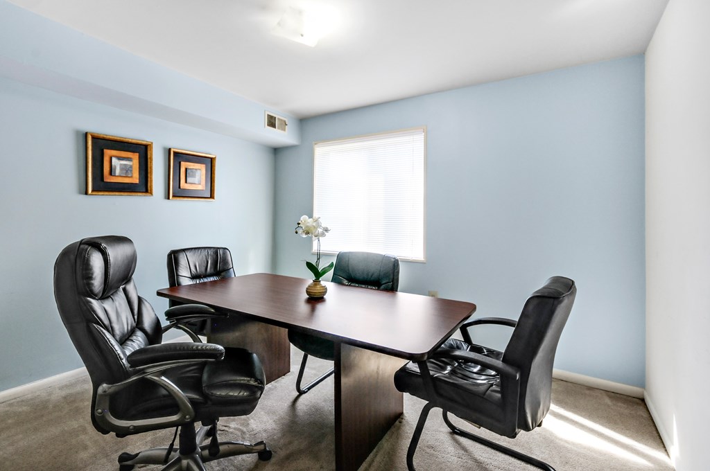 A conference room with a table and four chairs.