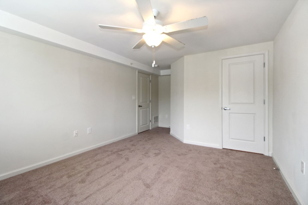 an empty living room with a ceiling fan and white walls