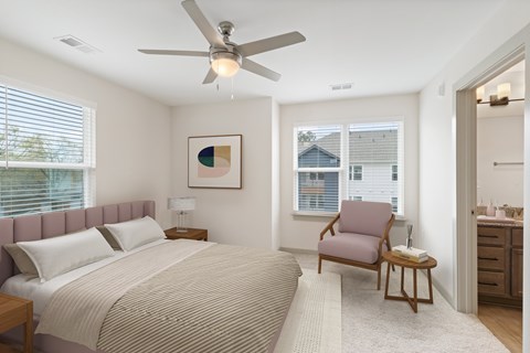 A bedroom with a bed, chair, and a painting on the wall.