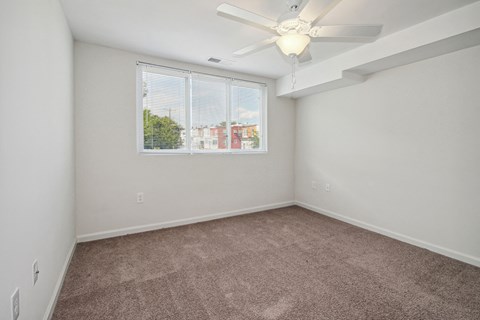 an empty bedroom with a ceiling fan and a window